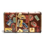 A vintage travel trunk with beechwood banding and metal brackets, various travel stickers,