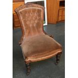 A buttonback low bedroom chair, carved rail on turned legs and casters