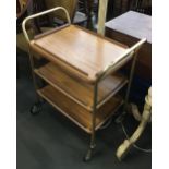 A metal framed three tiered tea trolley with removable tray on large casters