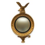 A Regency giltwood and gesso convex wall mirror, the circular plate within an ebonised reeded slip