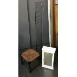 A small bathroom cabinet with mirror, together with a wicker stool and metal CD rack