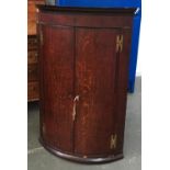 A George III bowfront oak corner cupboard, 103cmH