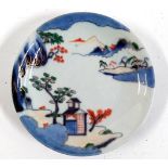 A Japanese porcelain plate, decorated sansui mountain scenery, in blue, green and red, heightened in