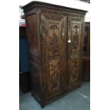 A heavily carved armoire, two cupboard doors carved with acanthus decoration, baskets of flowers and