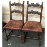 A pair of carved oak dining chairs with leather seats