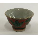A Japanese Yakimono sake cup, Guinomi Kutani ware, green Karako design on a red background, marks to