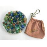 A collection of various marbles, mainly cats eye swirl, with embroidered storage pouch