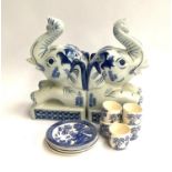 A pair of ceramic elephant bookends, together with four blue and white willow pattern coasters and