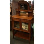 An early 20th century sideboard with mirrored superstructure over two glazed doors with key and