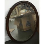 An oak framed oval wall mirror with bevelled glass, 67x52cm