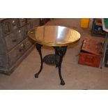 A circular brass topped pub table with mask decora