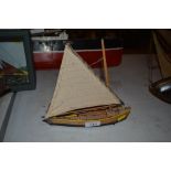 A wooden model of a small sailing/rowing boat