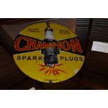 A circular enamel sign for "Champion Spark Plugs"