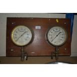 Two vintage pressure gauges mounted on a wooden pl