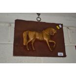 A metal horse on a wooden plaque