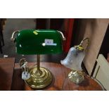 A brass desk lamp with green glass shade and one o