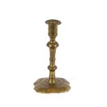 A mid 18th Century seamed brass candlestick, with tapered knopped stem and petal style base, 17.