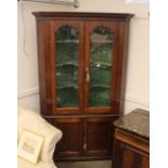 A good quality oak standing corner cabinet, the upper display shelves enclosed by a pair of glazed