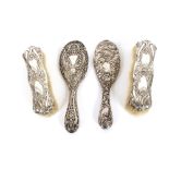 A pair of silver backed Art Nouveau brushes, and two silver backed hand mirrors
