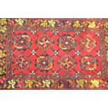 A small Eastern rug, having stylised floral decoration on a red ground, 103cm x 55cm