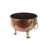 An Antique copper circular jardiniére, flanked by brass lion mask handles and raised on paw feet,