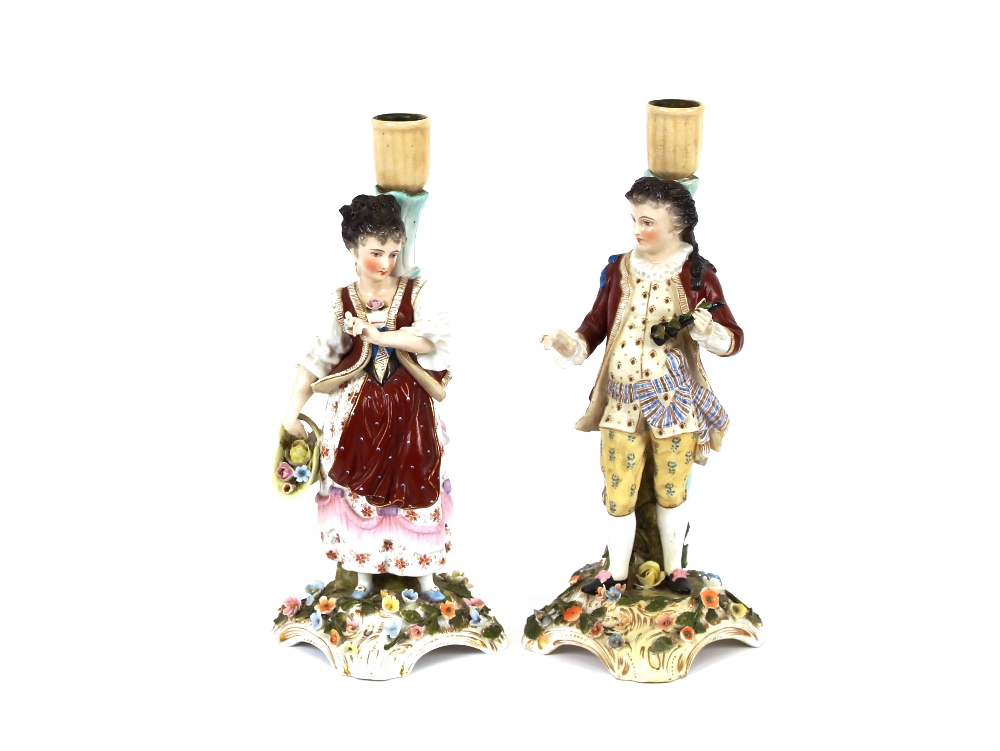 A pair of Continental porcelain figural candlesticks, in the form of a maid and youth, raised on