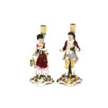 A pair of Continental porcelain figural candlesticks, in the form of a maid and youth, raised on