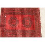 A small Eastern mat, having stylised decoration on a deep red ground, 84cm x 66cm