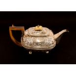 A George III silver teapot, having raised foliate embossed decoration and vacant cartouche, ivory