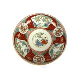 An Imari pattern shallow bowl, decorated with panels of foliage and symbols, heightened in gilt,
