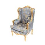A French style gilt wing back salon armchair, having leaf decoration, with floral printed damask