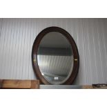 An oak framed bevelled edged oval wall mirror