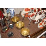 A graduating set of three brass saucepans