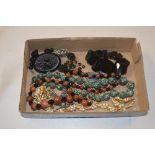 A tray containing a jet brooch; costume necklaces