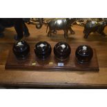 A set of four Lignum Vitae bowling woods on stand