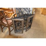 An ornate metal folding fire screen