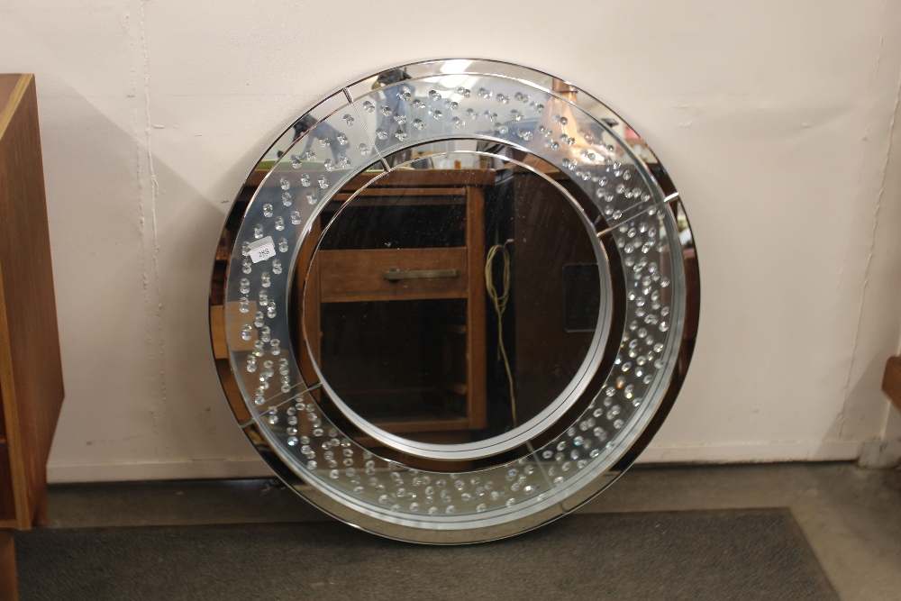 A circular silvered and diamante decorated wall mi