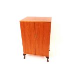 A pair of teak side cabinets raised on cabriole su