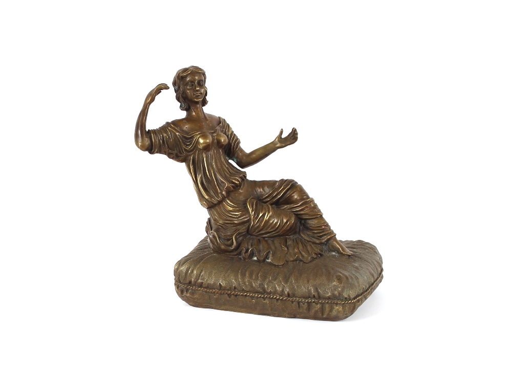 A bronzed figure of a lady, reclining on a cushion