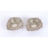 A pair of silver heart shaped pin dishes with flor