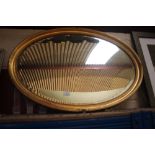An oval gilt framed bevel edged wall mirror