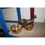 A set of three brass and iron graduated saucepans
