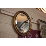 An oval gilt framed bevel edged wall mirror