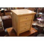 A light oak three drawer bedside chest