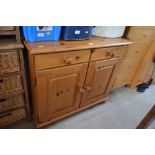 A pine side cupboard fitted two drawers above