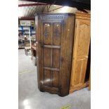 A carved oak upright corner cupboard