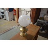 A brass oil lamp with opaque glass shade
