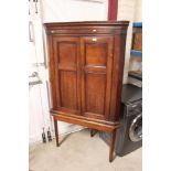 A George III oak corner cupboard on stand