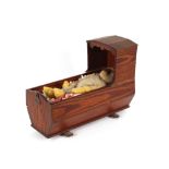 An Antique grained pine doll's crib, 47cm long x 34cm high, containing a vintage monkey toy and