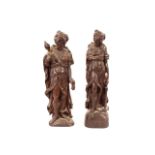 A pair of Jacobean carved oak figures, depicting a lady semi naked carrying a torch and another
